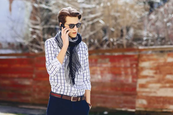 Güneş gözlüğü ile telefon şık genç adam sokakta yürümek