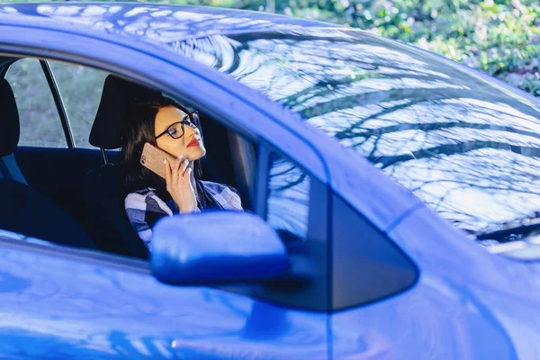 Kız araba ve günbatımı ışığında telefonla konuşurken direksiyonda oturan