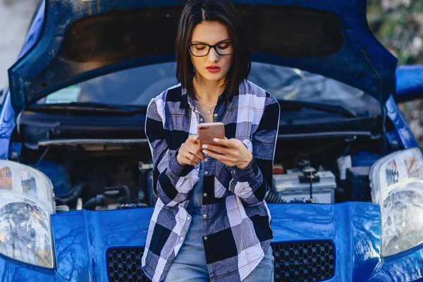 Açık yolda araba kaputuna telefon ile çekici kız