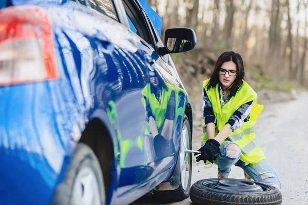 çekici kız Road parlak güvenlik ceketle yalnız araba tekerleği kaldırmak