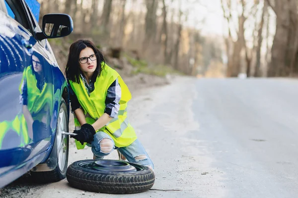 çekici kız Road parlak güvenlik ceketle yalnız araba tekerleği kaldırmak