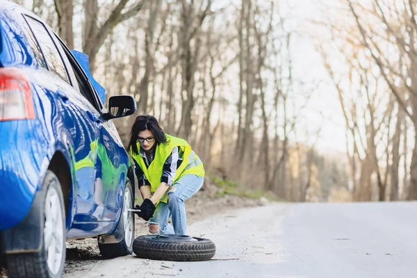 çekici kız Road parlak güvenlik ceketle yalnız araba tekerleği kaldırmak