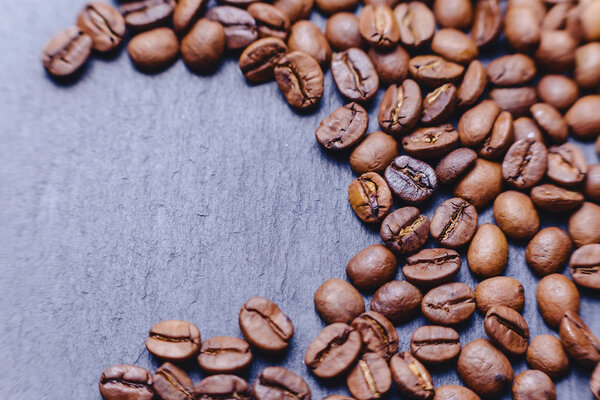 Coffee beans on black stone background with empty place closup