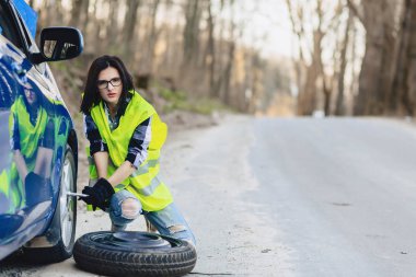 çekici kız Road parlak güvenlik ceketle yalnız araba tekerleği kaldırmak