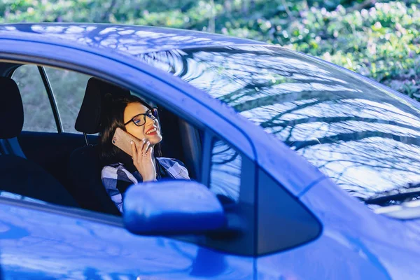 Kız araba ve günbatımı ışığında telefonla konuşurken direksiyonda oturan