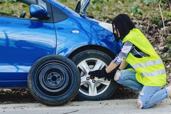 çekici kız Road parlak güvenlik ceketle yalnız araba tekerleği kaldırmak