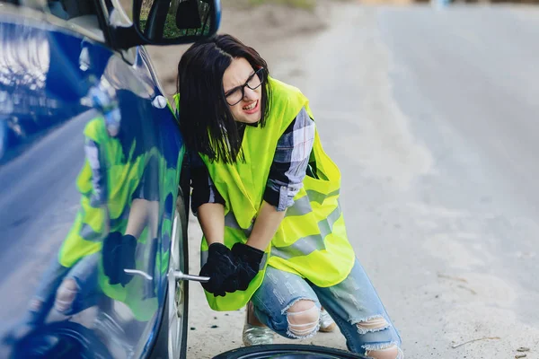çekici kız Road parlak güvenlik ceketle yalnız araba tekerleği kaldırmak