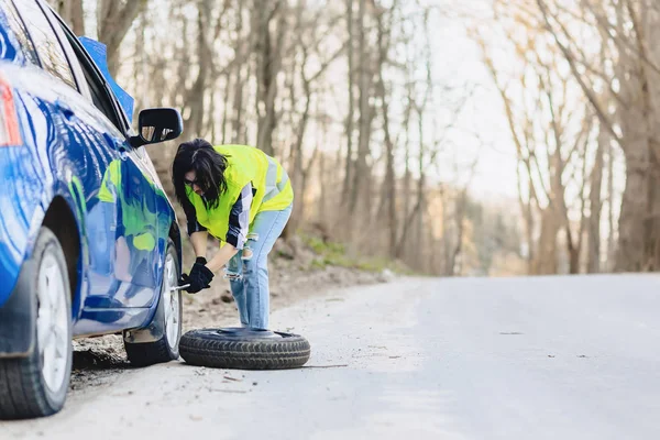 çekici kız Road parlak güvenlik ceketle yalnız araba tekerleği kaldırmak