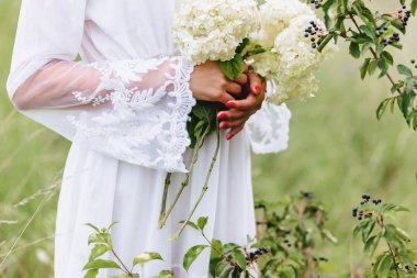 Genç güzel kız ile hafif soyunma yürüyüş Lawn yeşil yaz forest yakınındaki ellerinde çiçek