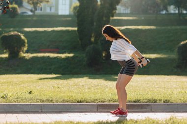 çim dışında gün batımında dumbbells ile egzersizleri yapma rahat fitness kız
