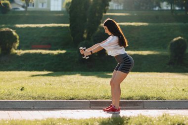 çim dışında gün batımında dumbbells ile egzersizleri yapma rahat fitness kız