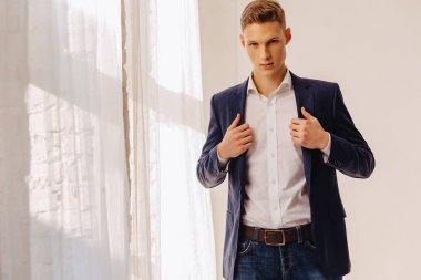 anıtsal yüzü aydınlık iç, moda, iş aksanı olan bir kostüm ceketli şık genç çocuk