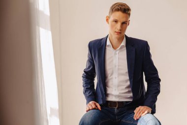 anıtsal yüzü aydınlık iç, moda, iş aksanı olan bir kostüm ceketli şık genç çocuk