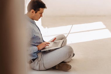 yerdeki ışık güneşli iç, serbest meslek, dizüstü dizüstü bilgisayar üzerinde çalışan genç şık adam