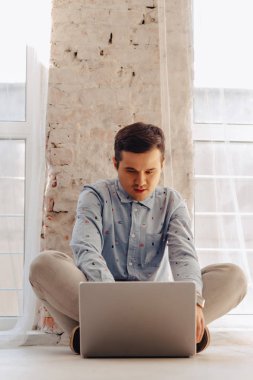 yerdeki ışık güneşli iç, serbest meslek, dizüstü dizüstü bilgisayar üzerinde çalışan genç şık adam