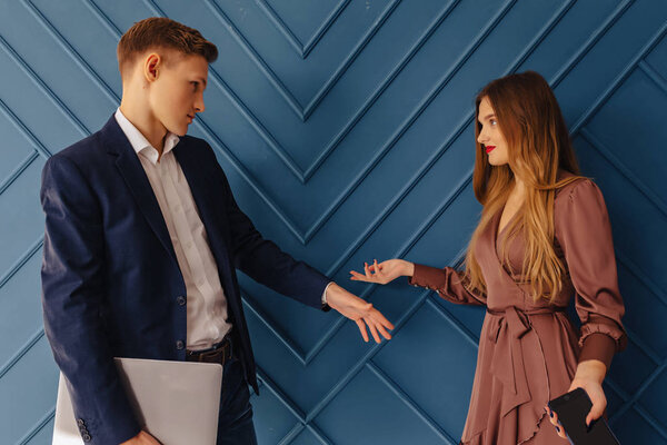 stylish young guy with laptop and girl with phone emotions, young businessman, freelancer work, simple aqua background