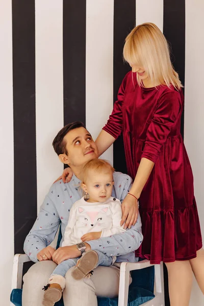 beautiful family with a small daughter, a simple background, happiness and joy in apartments