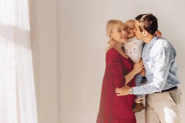 beautiful family with a small daughter, a simple background, happiness and joy in apartments