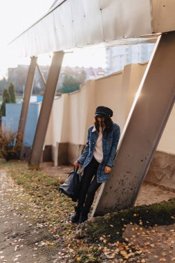 Sonbahar güneşli şehirde bir kot ceket genç güzel kız yürüyor