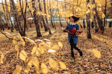 Genç güzel kız bir kot ceket sonbahar güneşli parkta yürüyor