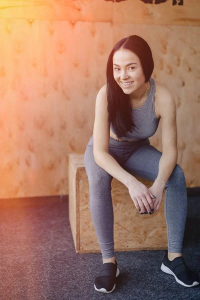 Young girl in sportswear in a gym in a simple background, a theme of fitness, a crossfit and sport — Stock Photo, Image