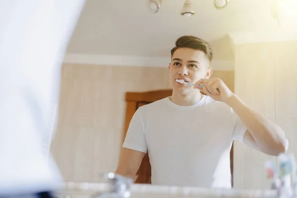 Higiene da manhã, o menino escova os dentes perto do espelho — Fotografia de Stock