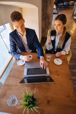 Sabah kahvesi kafe ve inşaat ile bir dizüstü bilgisayar, Genç İşadamları ve serbest şık bir çift içecekler