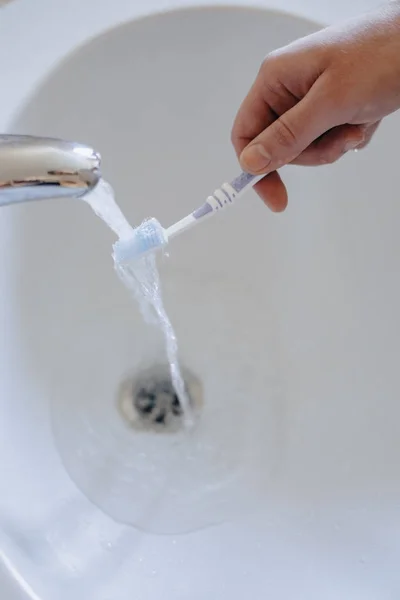 içinde lavabo su akışı altında diş fırçası yıkama