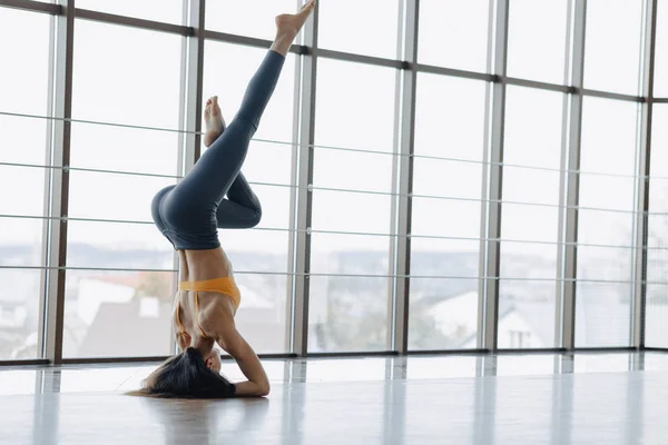 Jeune fille attrayante faisant des exercices de fitness avec yoga sur le sol sur le fond de fenêtres panoramiques — Photo