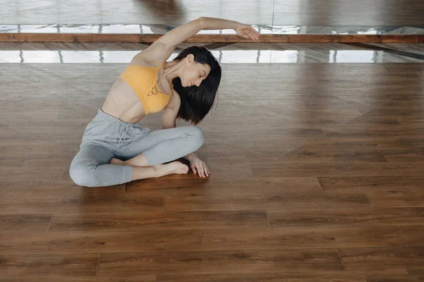 Joven chica atractiva en un piso de madera haciendo yoga, estiramiento y relajante —  Fotos de Stock