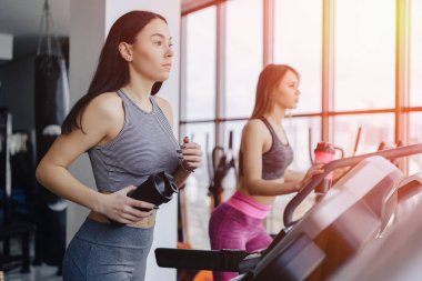 Kızlar spor salonunda koşu bandı ve içecek su, eğitimli gülümseyen