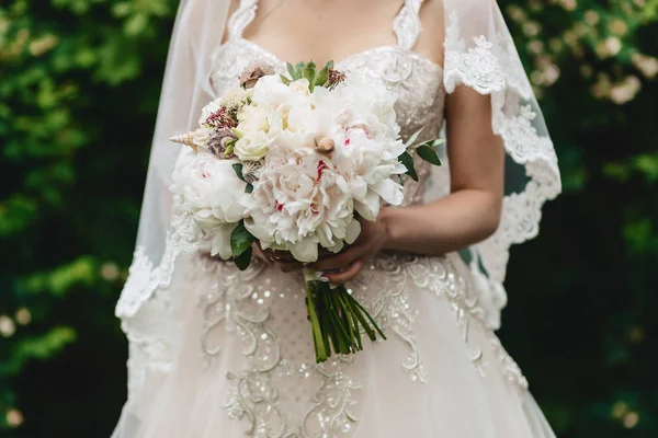 A noiva segura um buquê de casamento em suas mãos — Fotografia de Stock