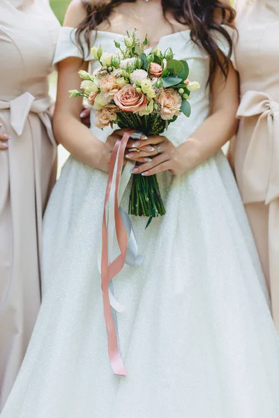 A noiva segura um buquê de casamento em suas mãos — Fotografia de Stock