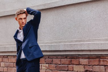 ahşap ve taş duvarları yakınında sakin bir şehirde anıtsal bir yüz ile genç şık adam yürüyor