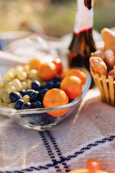 summer picnic on a rug with fruits, wine and tea, cups, croissants and sweets details