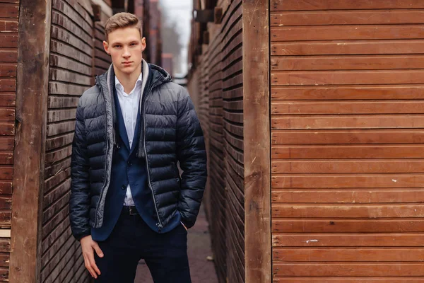 Ung snygg kille med en monumental ansikte promenader i en cool stad nära den trä och sten väggar — Stockfoto