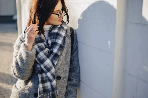 Rapariga atraente usando óculos em um casaco andando em um dia ensolarado — Fotografia de Stock