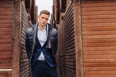 ahşap ve taş duvarları yakınında sakin bir şehirde anıtsal bir yüz ile genç şık adam yürüyor