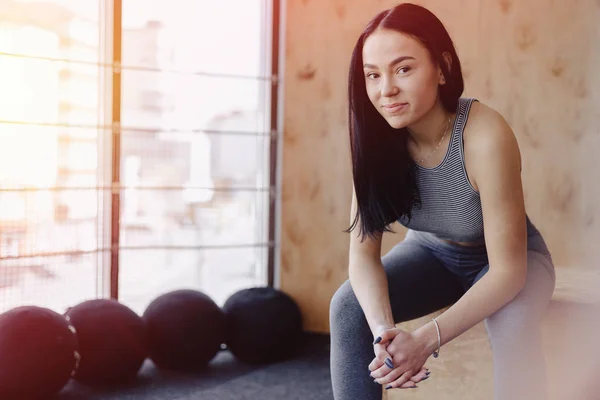 Jong meisje in sportkleding in een sportschool op een eenvoudige achtergrond, een thema van fitness, een crossfit en sport — Stockfoto