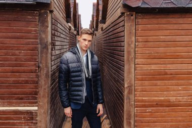 ahşap ve taş duvarları yakınında sakin bir şehirde anıtsal bir yüz ile genç şık adam yürüyor