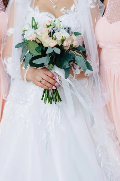A noiva segura um buquê de casamento em suas mãos — Fotografia de Stock