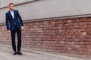 ahşap ve taş duvarları yakınında sakin bir şehirde anıtsal bir yüz ile genç şık adam yürüyor