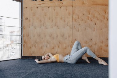 Ahşap bir arka planda yerde Yoga ile Fitness egzersizleri yapan genç çekici kız