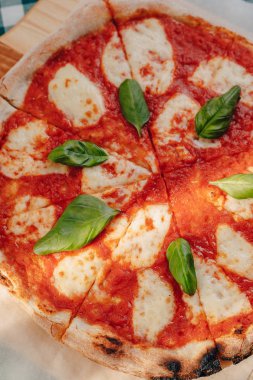 Jambon ile Napoliten Pizza, peynir, Arugula, fesleğen, domates metin için bir yer ile bir hücrede bir masa örtüsü üzerinde bir ahşap tahta üzerinde peynir serpilir