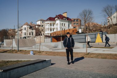 turuncu gözlük, ceket ve kap şık genç çocuk, ilkbahar veya sonbaharda göl etrafında yürümek