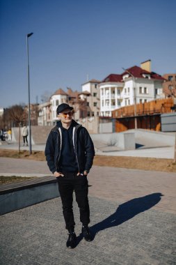 turuncu gözlük, ceket ve kap şık genç çocuk, ilkbahar veya sonbaharda göl etrafında yürümek
