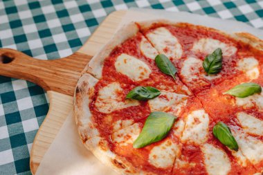 Jambon ile Napoliten Pizza, peynir, Arugula, fesleğen, domates metin için bir yer ile bir hücrede bir masa örtüsü üzerinde bir ahşap tahta üzerinde peynir serpilir