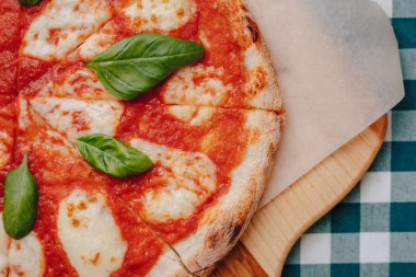 Jambon ile Napoliten Pizza, peynir, Arugula, fesleğen, domates metin için bir yer ile bir hücrede bir masa örtüsü üzerinde bir ahşap tahta üzerinde peynir serpilir