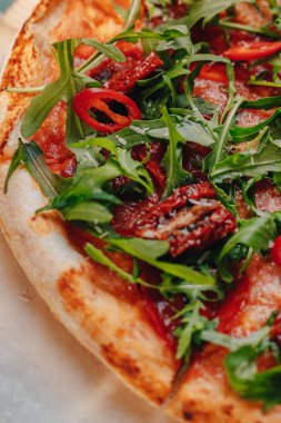 Jambon, peynir, Arugula, fesleğen, domates, pepperoni biber ile Napoliten Baharatlı pizza metin için bir yer ile bir hücrede bir masa örtüsü üzerinde bir ahşap tahta üzerinde peynir ile püskürtülmüş