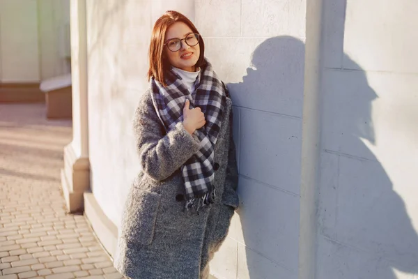 Rapariga atraente usando óculos em um casaco andando em um dia ensolarado — Fotografia de Stock